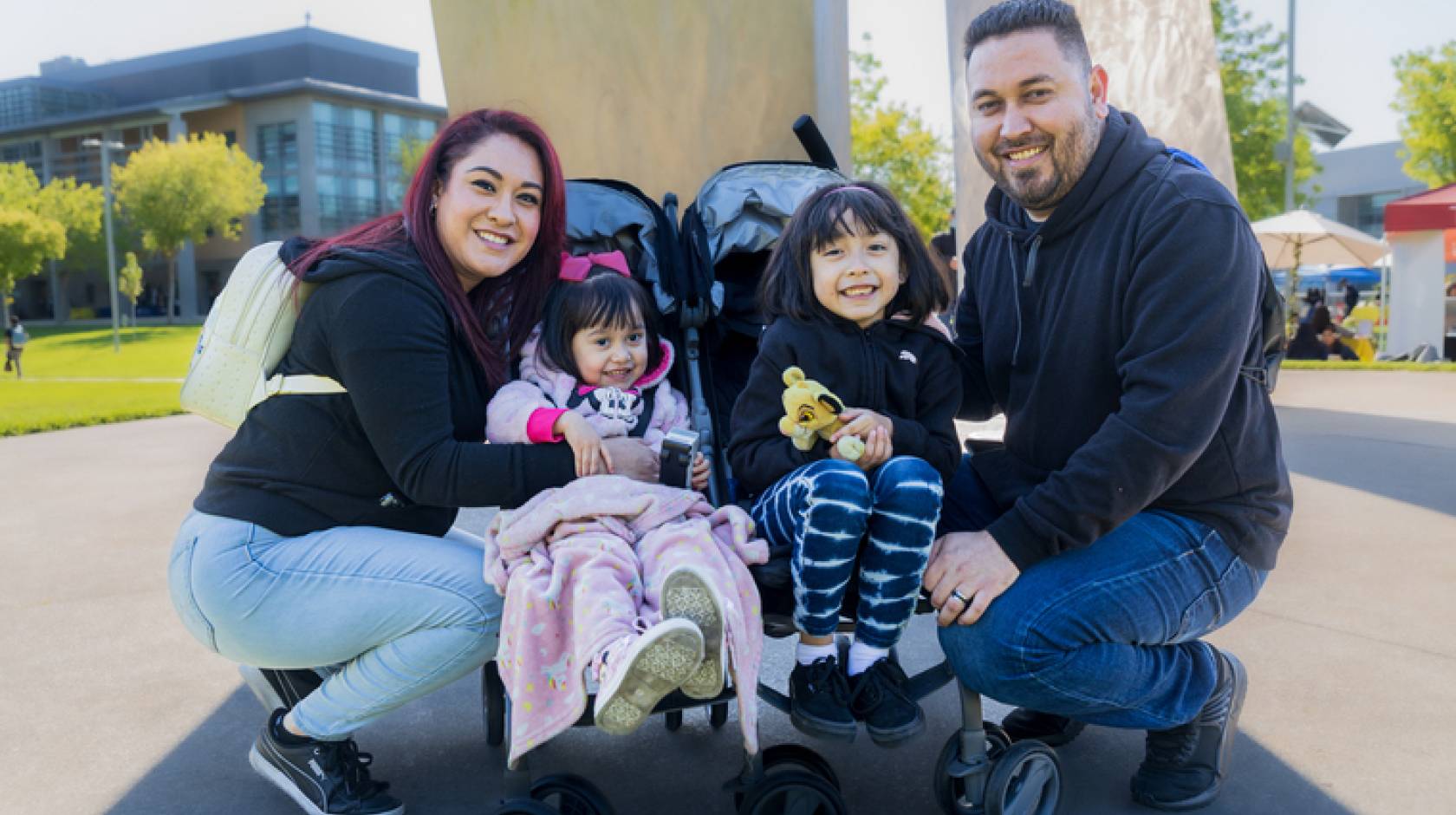 A family with two parents and two young children in a stroller